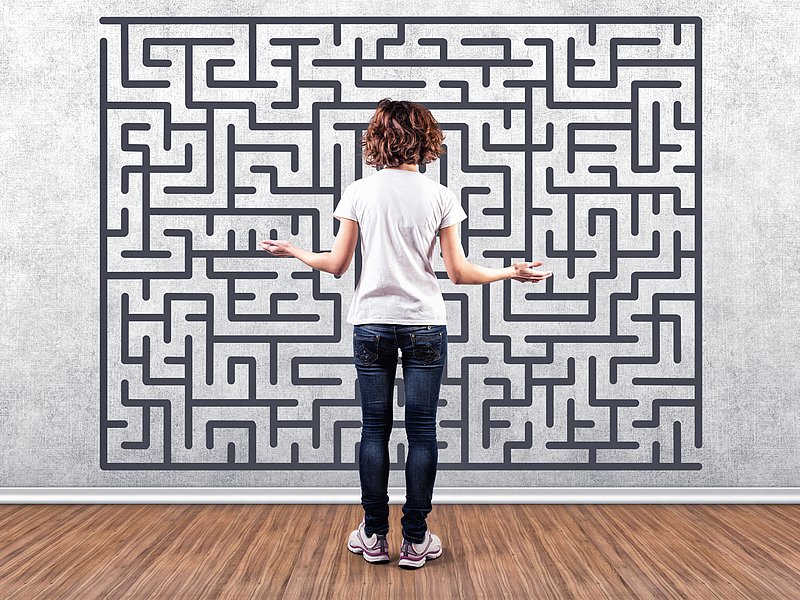 Frau steht ratlos vor einem aufgemalten Labyrinth