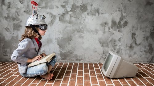 Kind mit Helm vor altmodischem Computer-Röhrenbildschirm