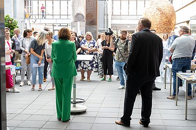 Frau in grün und Mann in schwarz gekleidet stehen vor einem Publikum