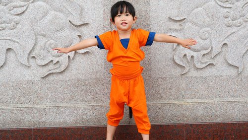 Kleines asiatisch aussehendes Kind mit seitlich ausgetreckten Armen