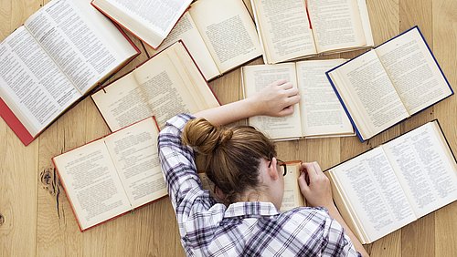 Frau, die erschöpft über ihren Studienbüchern liegt