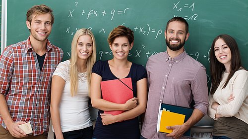 Gruppe junger Menschen vor einer Tafel mit mathematischen Formeln