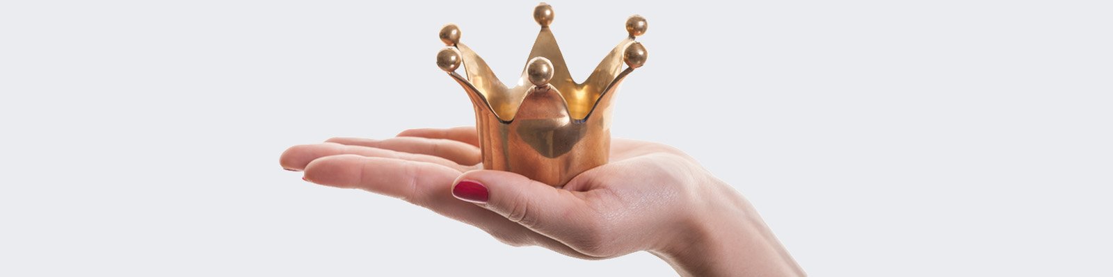 Frau hält eine goldene Krone auf ausgestreckter Handfläche krone_auf_hand_AdobeStock_46313095.jpg