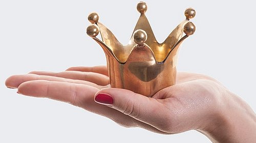 Frau hält goldene Krone auf ausgestreckter Handfläche